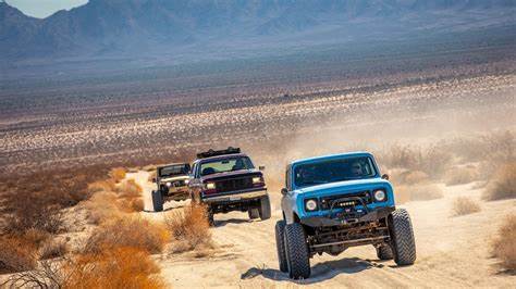 Multiple off-road vehicles racing across a desert landscape, kicking up dust clouds as they compete, representing the competitive spirit needed to qualify for treasure hunts.